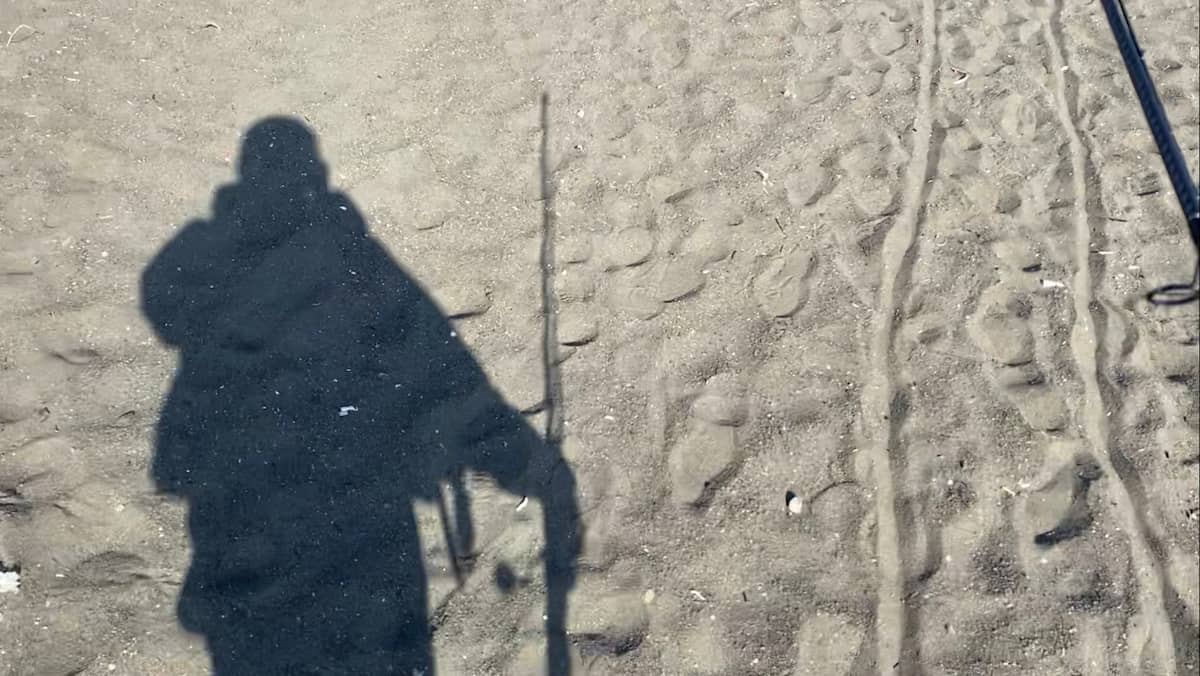 ロッドを持ってサーフを歩いているときの影。